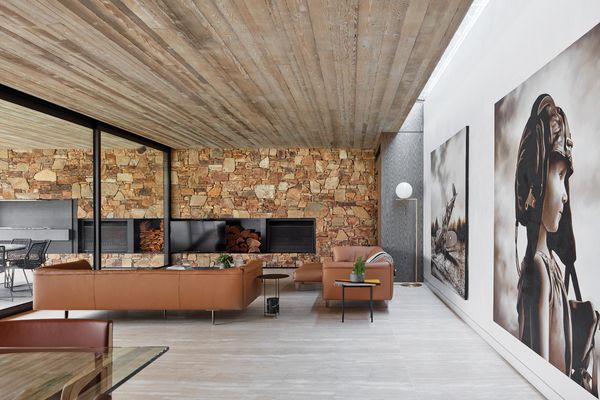 A stacked-stone feature wall provides a warm and textured backdrop to the living area, complemented by large-scale artworks. Artwork: Michael Peck.