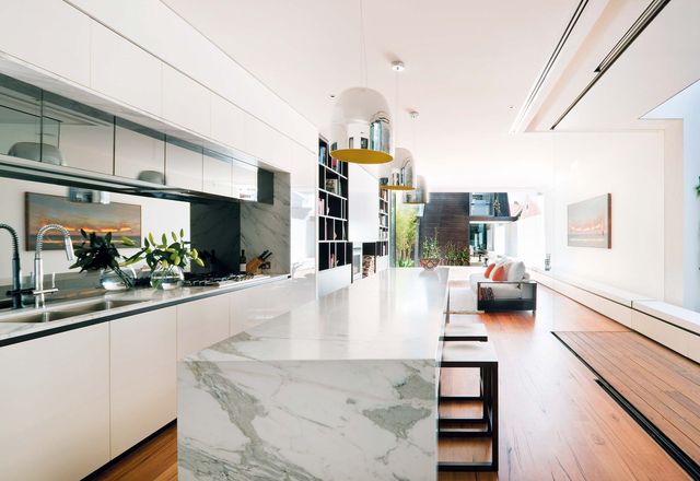 A light court beside the kitchen draws in light, while glazing and mirrors extend the sense of space.