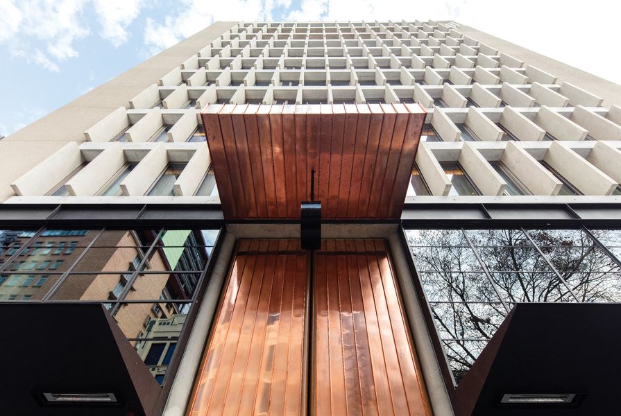 Two-part copper and timber doors, based on a Mexican cathedral, make for a grand and dramatic entry to the QT Melbourne hotel.