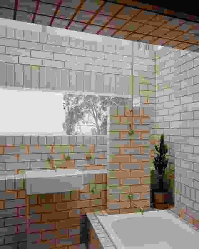 A playful outdoor bathroom of terracotta bricks with white glazed sides and ends is open to the fields beyond.