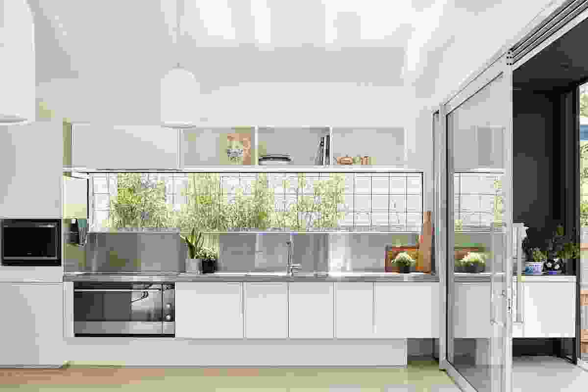 A framed view to garden plantings softens the clean lines of the kitchen, which is equipped with ample easy- to-access storage.