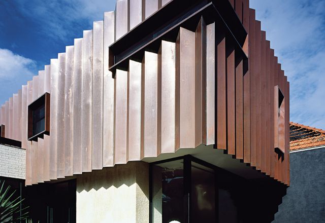 The addition’s pleated copper facade complements the tones of the existing red brick Federation house.
