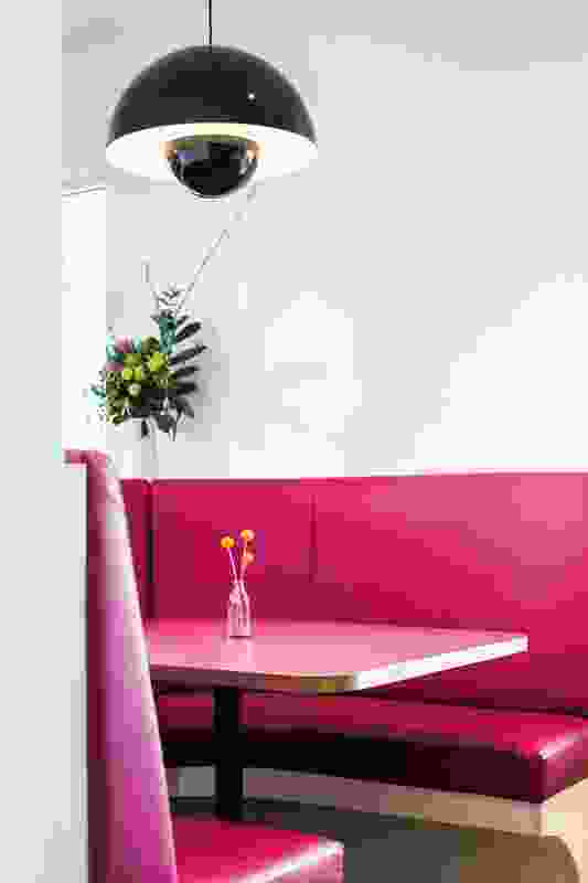 A custom-made hot pink circular booth creates a warm sanctuary in the middle of the front dining area.